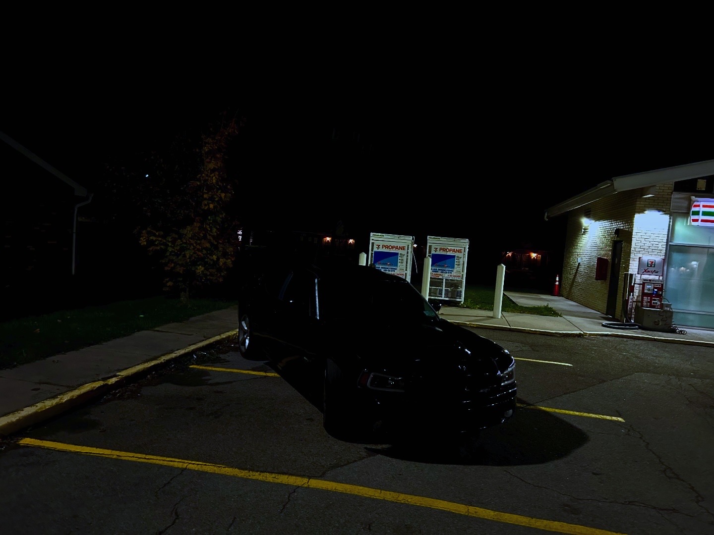 Black performance sedan photographed beside a city storefront