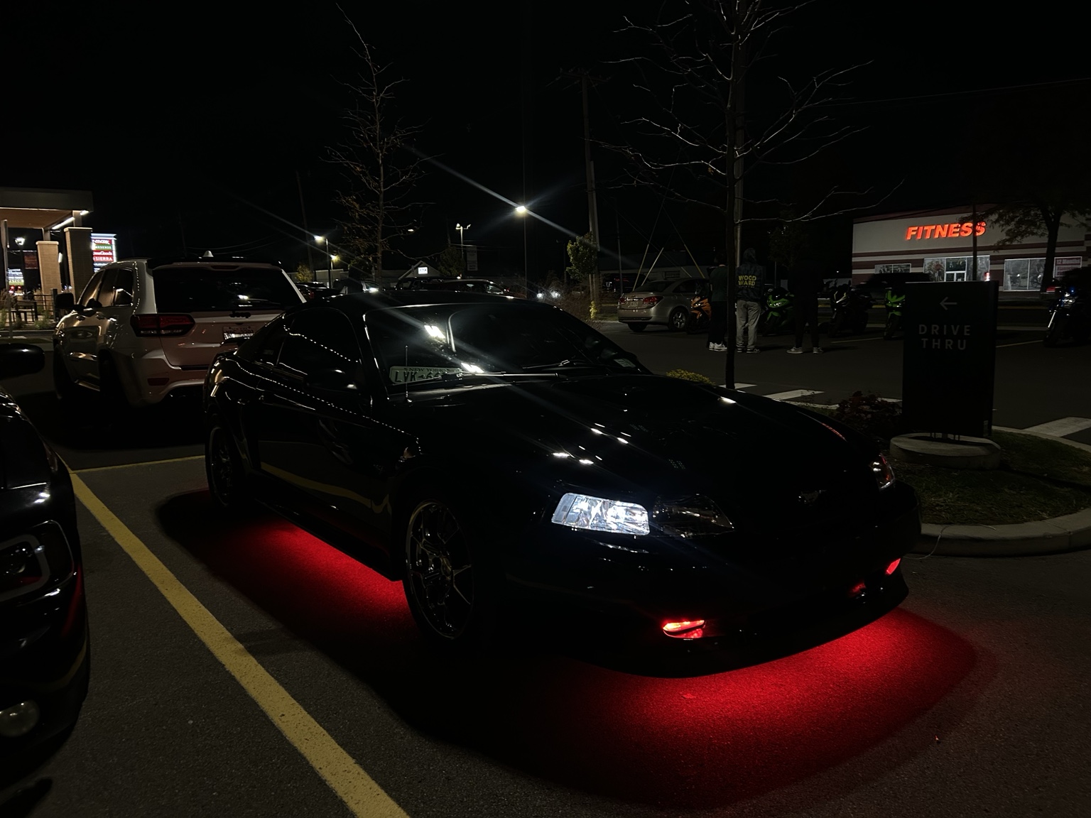 Black Mustang with red underglow photographed at a night meet