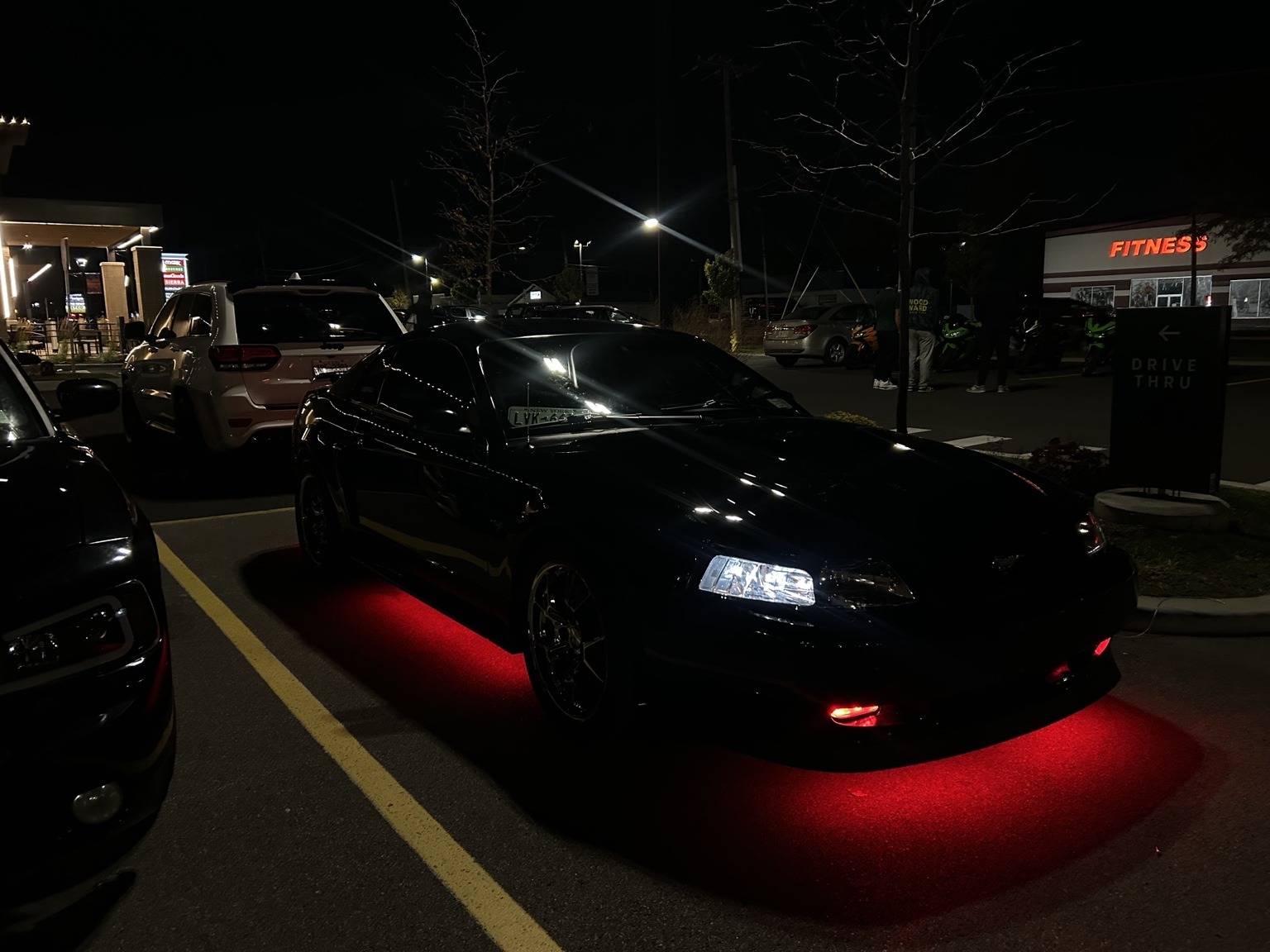 Wide front three-quarter view of a black Mustang with red underglow